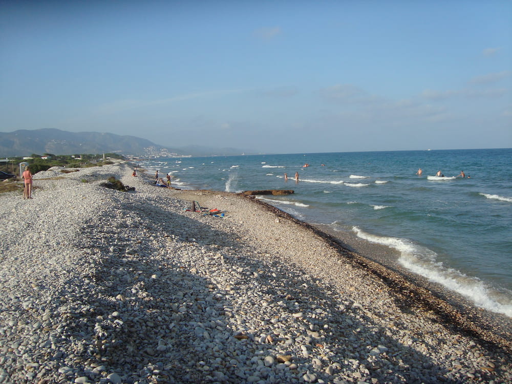 Отдаленный пляж с крупным песком и камнем